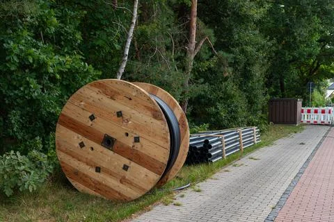 Large cable spools and construction materials beside a lane in summer Stock Photos