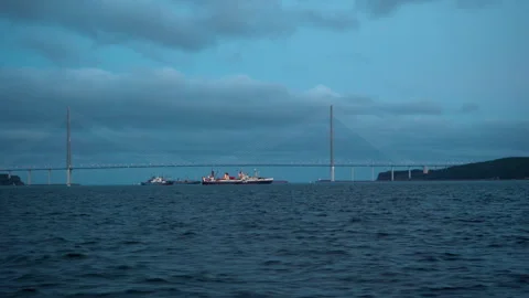 Large cable-stayed bridge at dusk. Vessels under bridge. View from water. Bridge Stock Footage 240844925