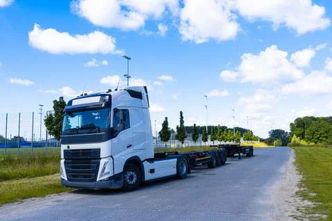 A large car with an empty semi-trailer standing on the side of the road. Stock Photos