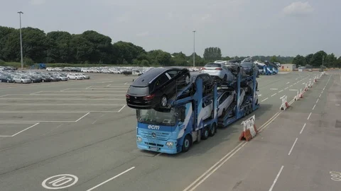 Large car transporter driving along road in industrial estate, drone aerial 4K Stock Footage 101120232