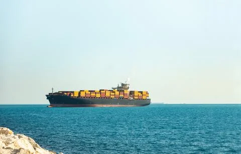 Large cargo container ship loaded with containers against the blue sky Stock Photos