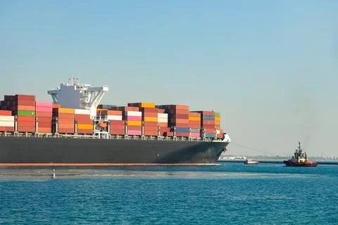 Large cargo container ship loaded with containers against the blue sky Stock Photos