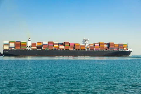 Large cargo container ship loaded with containers against the blue sky Stock Photos