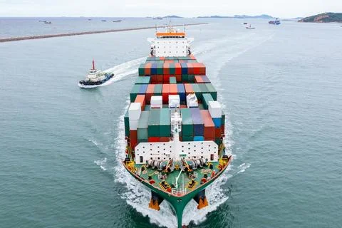 Large Cargo Container Ship Maneuvering With Tugboat Assistance At Port Entr.. Foto stock