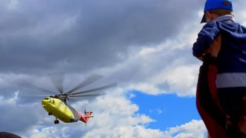 A large cargo helicopter hovered over people waiting to be evacuated. People are Stock Footage 212439650