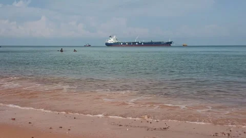 Large Cargo Ship Anchored Offshore with Swimmers and Ocean Waves Stock Footage 341180153