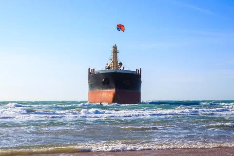 A large cargo ship on the Black Sea coast, kitesurfers on boards with a par.. Stockfoto's
