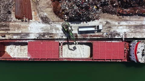 Large cargo ship at a dock being loaded with sand during the day in a busy Stock Footage 340142466