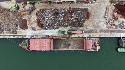 Large cargo ship docks at industrial port to unload materials in a busy harbor Stock Footage 337914494