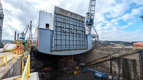 Large Cargo Ship in Dry Dock with Workers and Shipyard Cranes Stock Photos