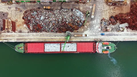 Large cargo ship loading materials at a busy port surrounded by scrap metal 스톡 동영상 340768709