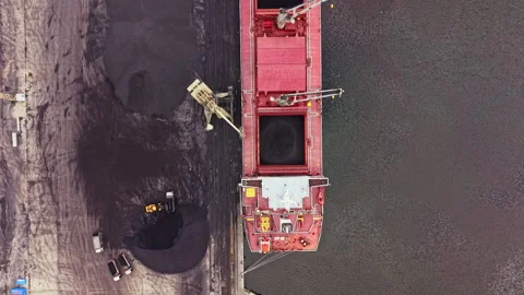 Large cargo ship loads coal at a dock near a river during daylight hours with Stock Footage 340882990