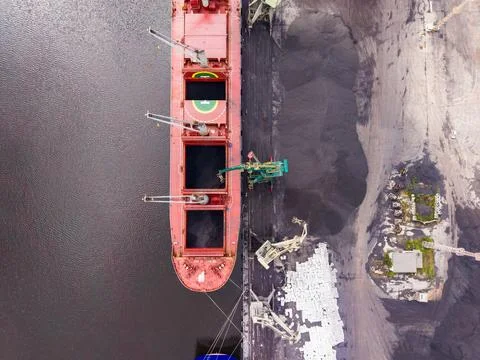 Large cargo ship loads materials at port during day with surrounding indust.. Stock Photos