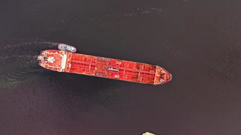 Large cargo ship moves through water with a tugboat assisting near the coast Stock Footage 340882373