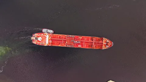 Large cargo ship moves through a waterway while a tugboat assists with Stock Footage 340882582