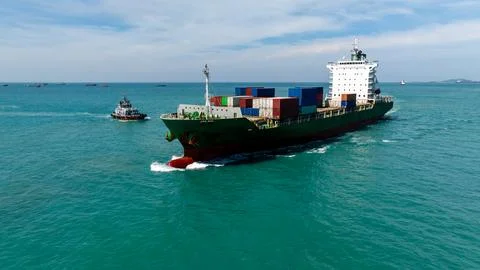 Large Cargo Ship Navigates Open Sea Accompanied By Tugboat Wide Shot Stock Photos