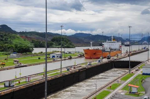 A large cargo ship navigates through the Panama Canal under a cloudy sky. Foto stock