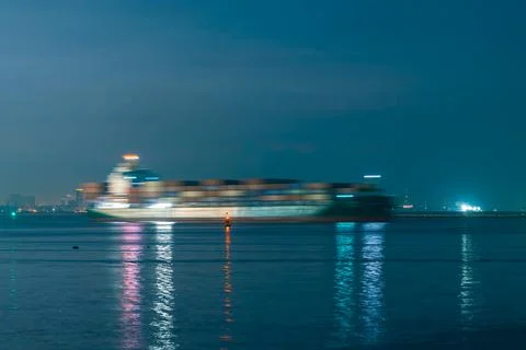 Large Cargo Ship Navigating City Coastline During Blue Hour Wide Shot Stock Photos