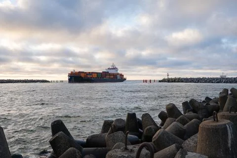 Large cargo ship navigating through rocky coastal waters under cloudy sky Stock Photos