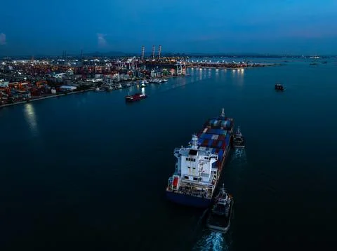 Large Cargo Ship Navigating Toward Port Terminal In Illuminated Harbor At T.. 写真素材