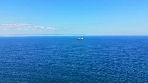 Large cargo ship sailing on the blue sea under a clear sky near a coastal area Stock Footage 344808512