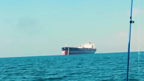 Large cargo ship sailing on the calm blue ocean seen from a fishing boat Stock Footage 312031485