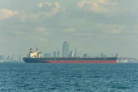 Large cargo ship sailing in the ocean with a Osaka city skyline in the back.. Stock Photos