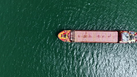 Large cargo ship sails on blue water near coastline during clear day, showing Stock Footage 337911678