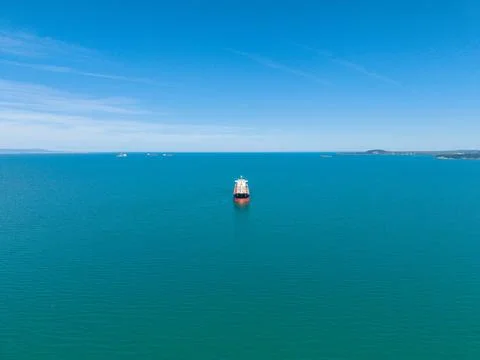Large cargo ship sails in clear blue ocean under bright sky Fotos de archivo