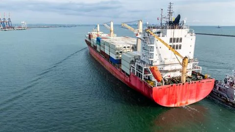 Large Cargo Ship Transiting Through A Busy Harbor Channel Wide Shot 库存照片