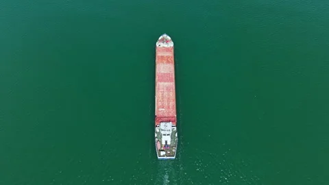 Large cargo ship travels through blue water while carrying containers under Stock Footage 337900656