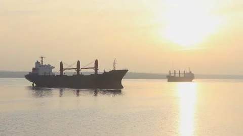 Large cargo ships at anchor sunset evening calm sea. Large ship coast orange sun Stock Footage 137255995