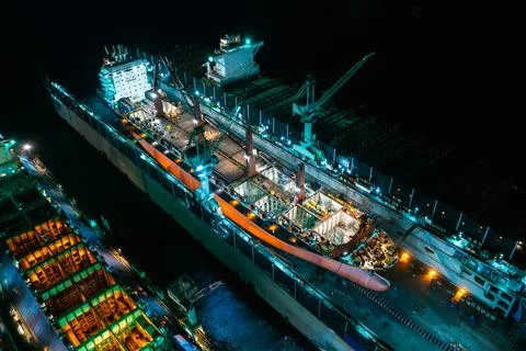 Large Cargo Vessel Undergoing Maintenance In Industrial Shipyard At Night H.. Foto stock