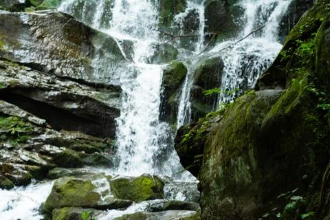 Large cascading waterfall in a mountain forest Stock Photos
