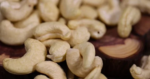 Large cashew nuts are scattered on a larch board, raw unroasted cashew nuts are Video stock 301692717