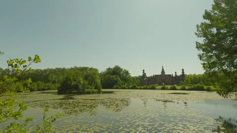 A large castle in the distance with many trees and a lake in the daylight. Stock Footage 244584879