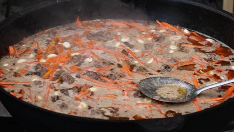 Large cauldron with boiling carrots and beef during outdoor cooking, food prepar Stock Footage 316905121