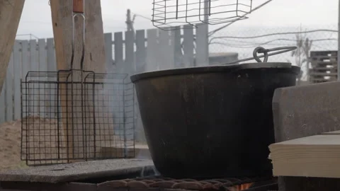 A large cauldron is on fire and there is smoke. cooking outside. Stock Footage 170426168