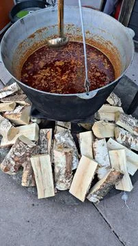 Large cauldron fixed over fire with delicious borscht cooked outdoors Stock Photos