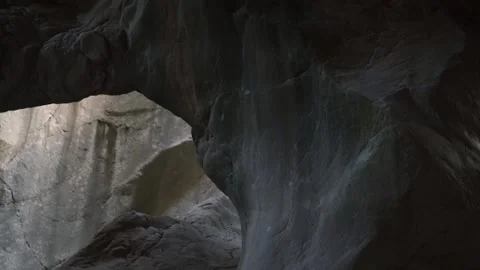 Large cave with rocks of strange form and hole to sunlight Stock Footage 143341617