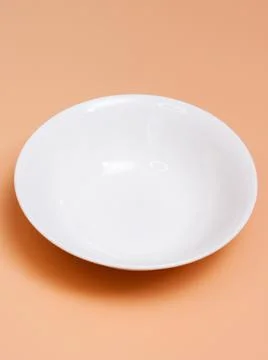 Large ceramic white empty bowl on an orange background. Top view. Stock Photos