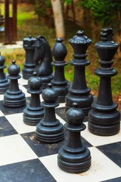 A large chess board featuring oversized giant chess pieces placed on it Stock Photos