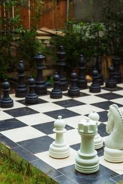 A large chess board featuring oversized giant chess pieces placed on it Stock Photos