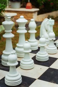 A large chess board featuring oversized giant chess pieces placed on it Stock Photos