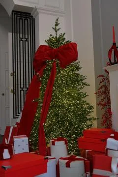 Large Christmas tree with red bow and toys. New Year's decor, gift box on Stock Photos