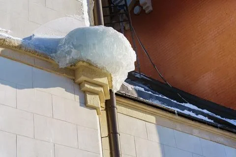 A large chunk of ice on the eaves of the building is ready to fall down Stock Photos
