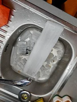 Large chunks of freezer ice collected in a kitchen sink Stock Photos