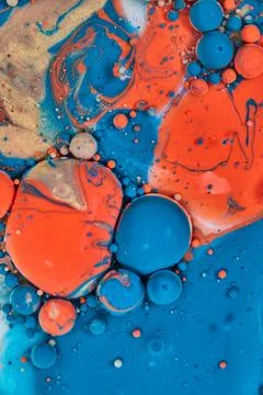Large circular blobs of blue orange and gold in abstract pour of acrylic paint Stock-Fotos