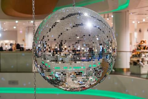 A large, circular disco ball hangs center in a modern commercial area with .. Stock Photos