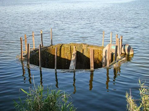 A large circular object partially submerged in water, possibly an old vesse.. Stock Photos